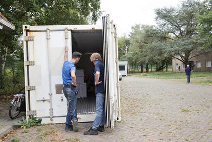 Medewerkers staan bij een container om te vullen met gebruikte spullen